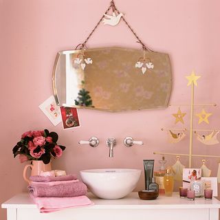 Pink bathroom scheme with a raised white vanity sink, bevelled mirror and vintage accessories