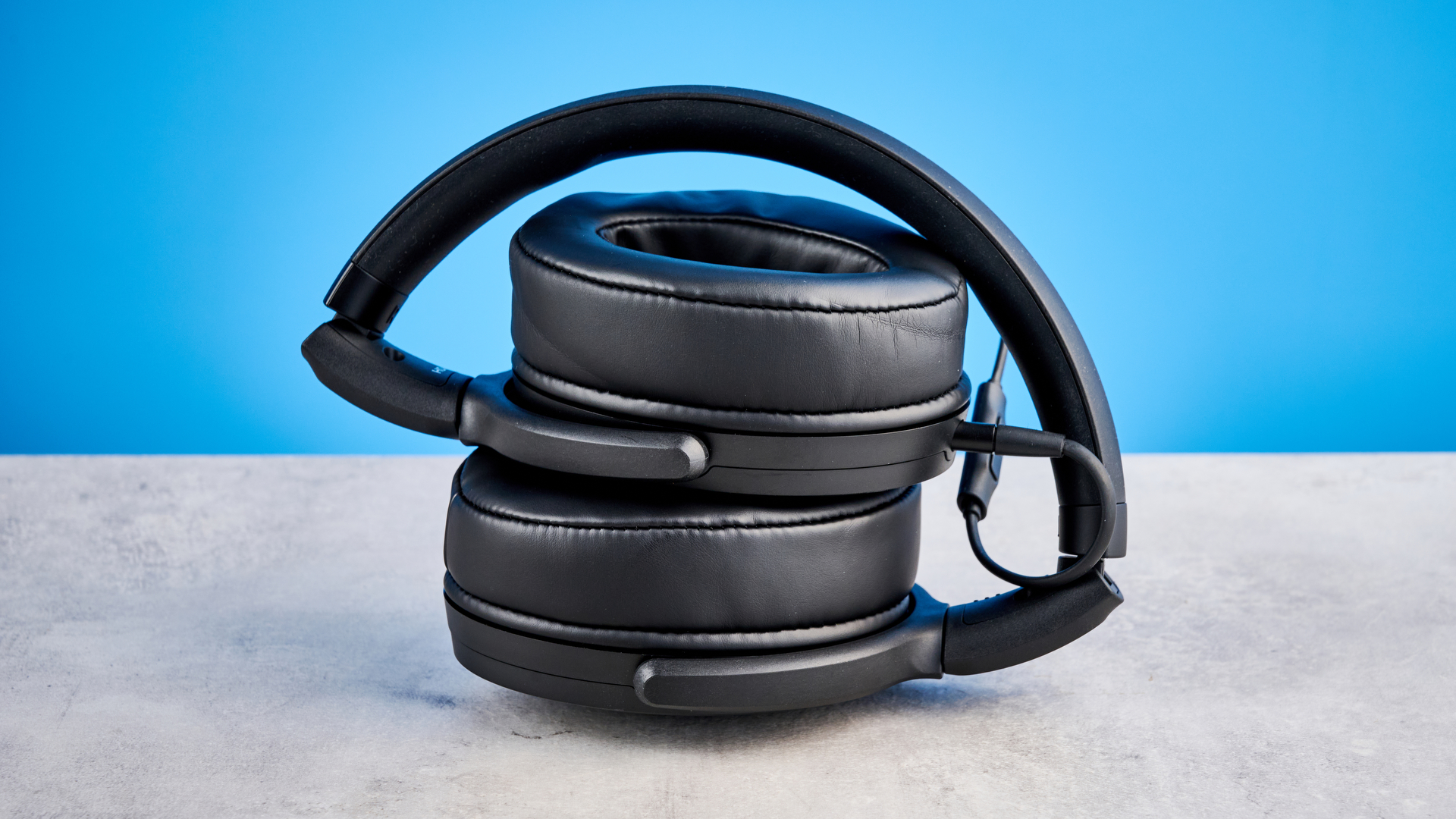 Sennheiser HD 400U on a stone surface with a blue background, the headphones are folded