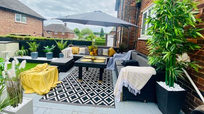 outdoor living space with seating in the form of two sofas, a black dining table, and a black and white rug