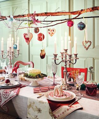 A dining table decorated with suspended branch and bauble decor