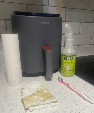 A Cosori air fryer with Mrs. Meyer's multi surface cleaning spray and paper towel