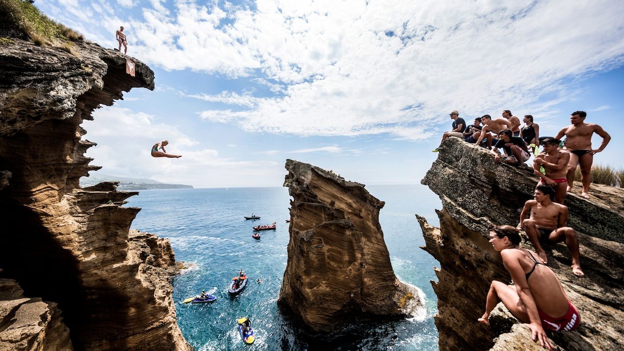 People diving from a cliff into water