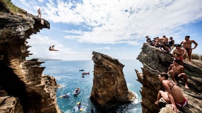People diving from cliffs into water