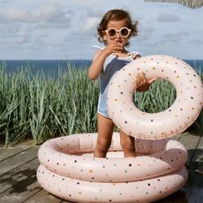 Little girl standing in an inflatable pool on a wooden deck