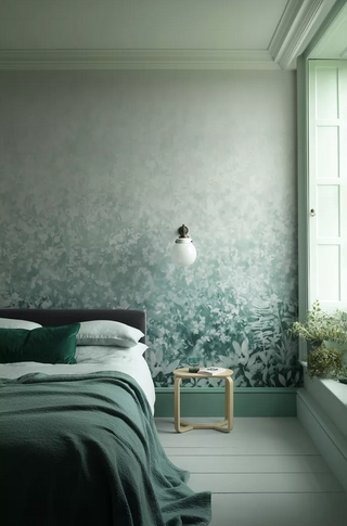 A pale sea-green scheme with cohesive colors, a leaf-print wallpaper and teal throw