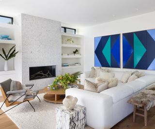 living room with white sectional, fireplace and blue artwork
