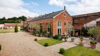 A barn conversion with lawned areas and a gravel driveway