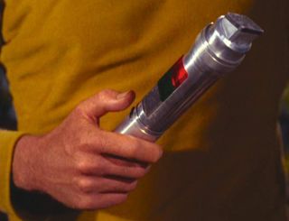 Screenshot from an episode of Star Trek with Captain Kirk holding a device used to translate alien languages.
