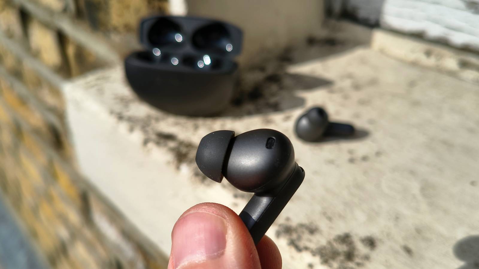 The OnePlus Buds 4 in a man's hands.