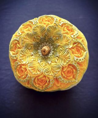 A pumpkin carving idea with intricate rose or floral design as seen on fruits and vegetables