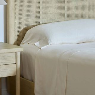 White Avec sheets on a white bed next to a nightstand