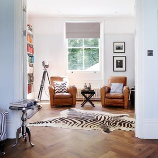 room with wooden floor and arm chair and rug and white wall