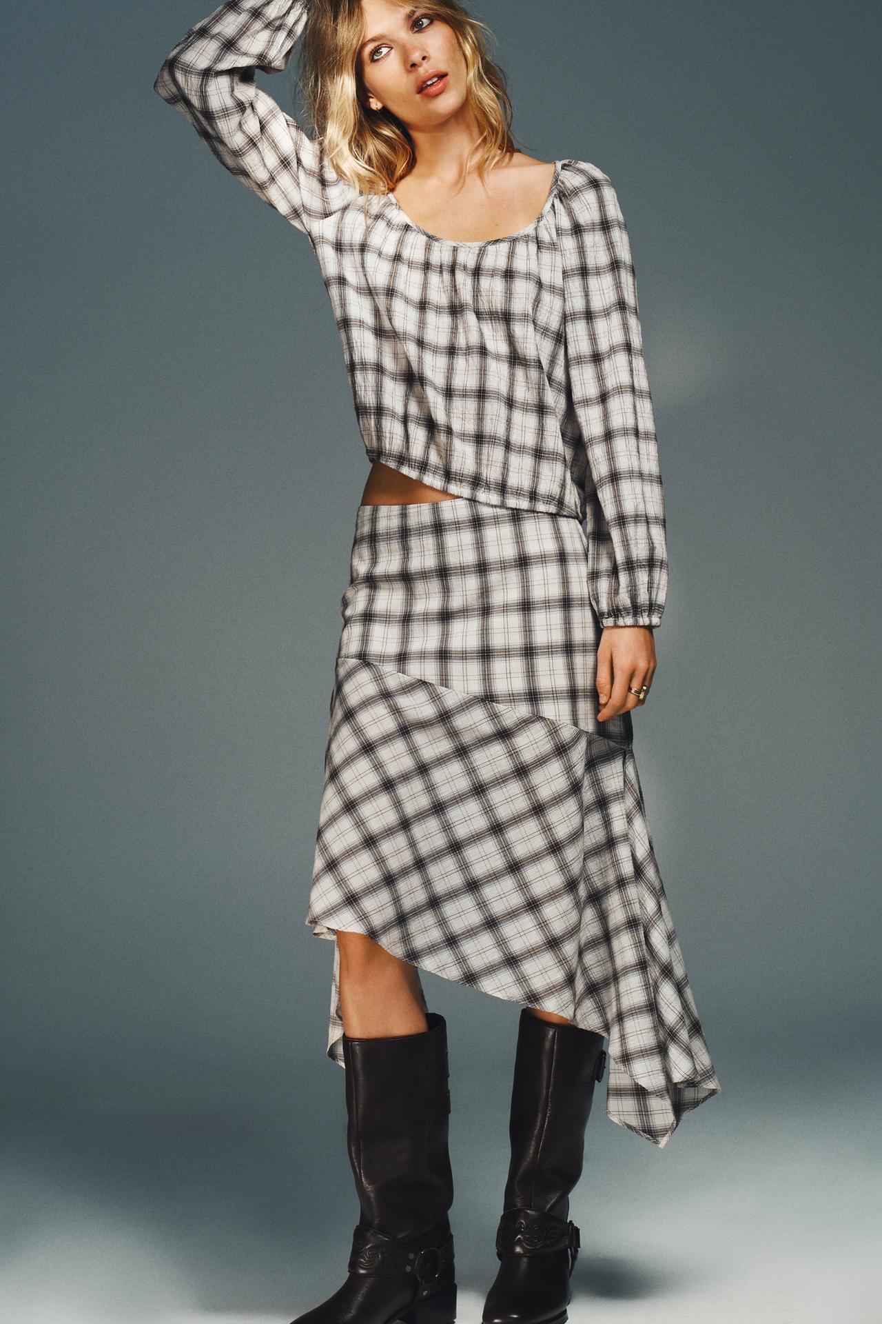 The Model wears a coordinating plaid Zara skirt set with tall black moto boots.