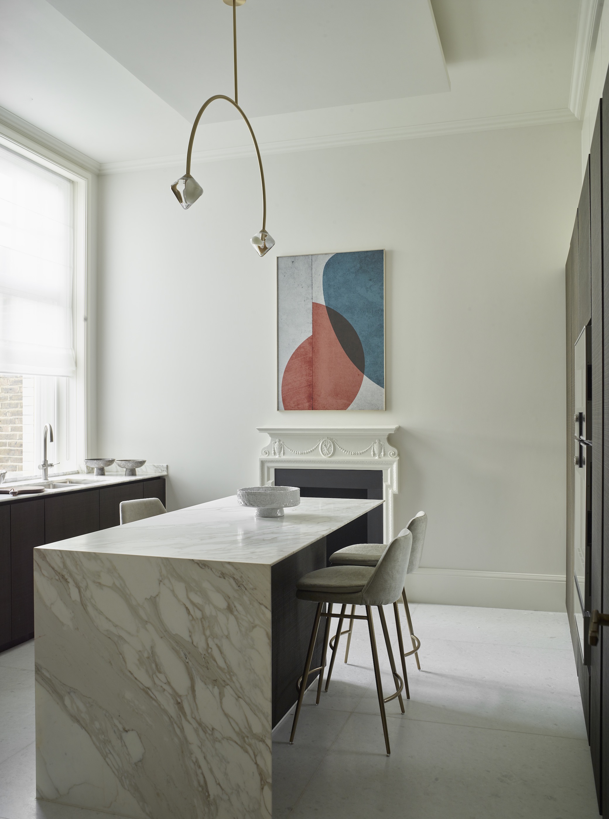 kitchen with slim marble island and modern art above fireplace