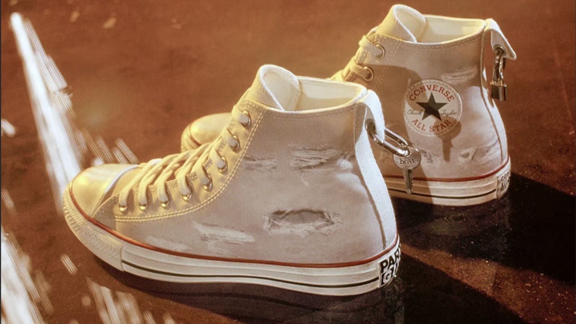 an image of the Charli XCX converse in white. They have distressed rips on the sides and heel charms on the back
