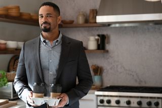 Damon Wayans Jr. as Derrick 2, holding a takeout tray of coffee while standing in a kitchen, in 'Shrinking.'