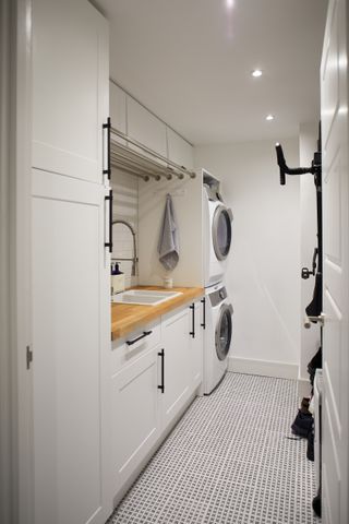 A monochrome utility room with laundry facilities stacked on top of each other and clever vertical bike storage