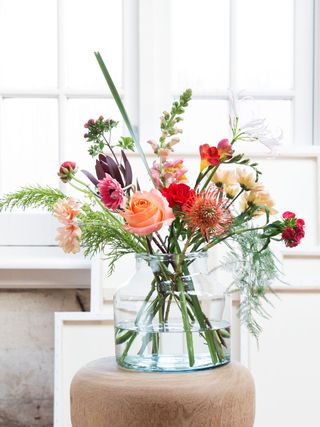 bouquet of flowers in glass vase in front of many windows
