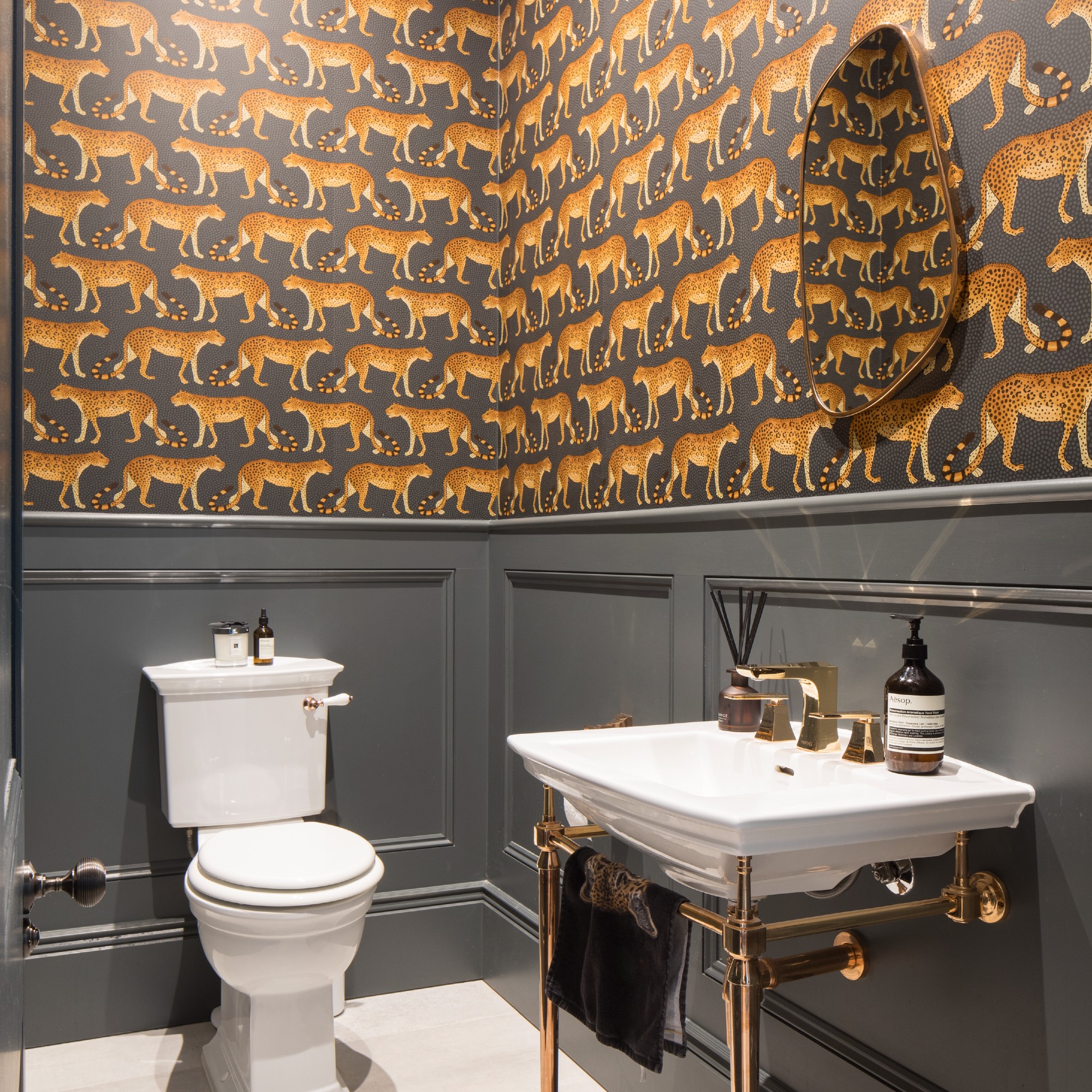 A cloakroom in charcoal grey covered in a leopard wallpaper