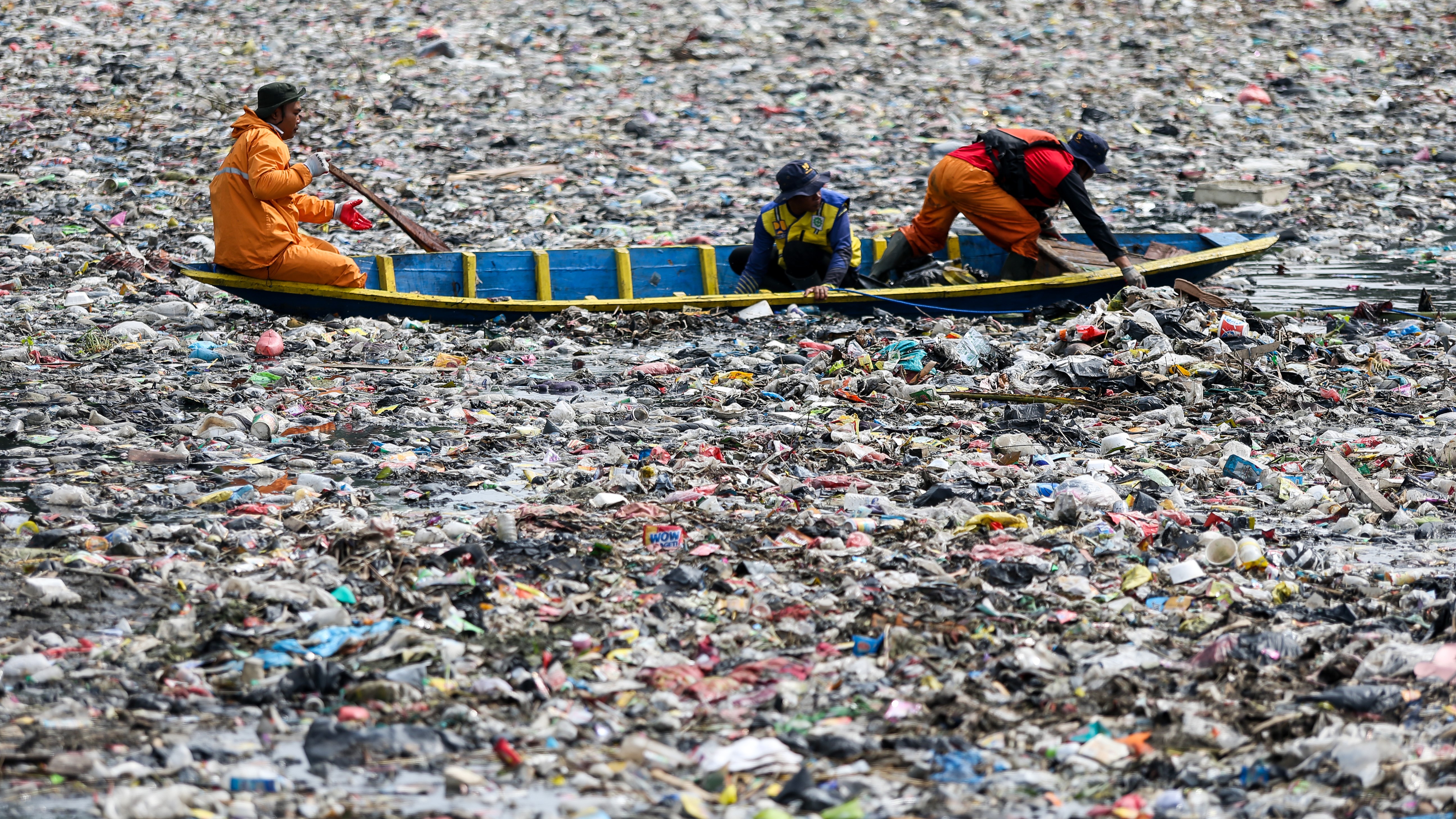 Ofițerii curăță grămezi de gunoi de plastic care plutesc în râul Cittarum din Bandung, Indonezia.