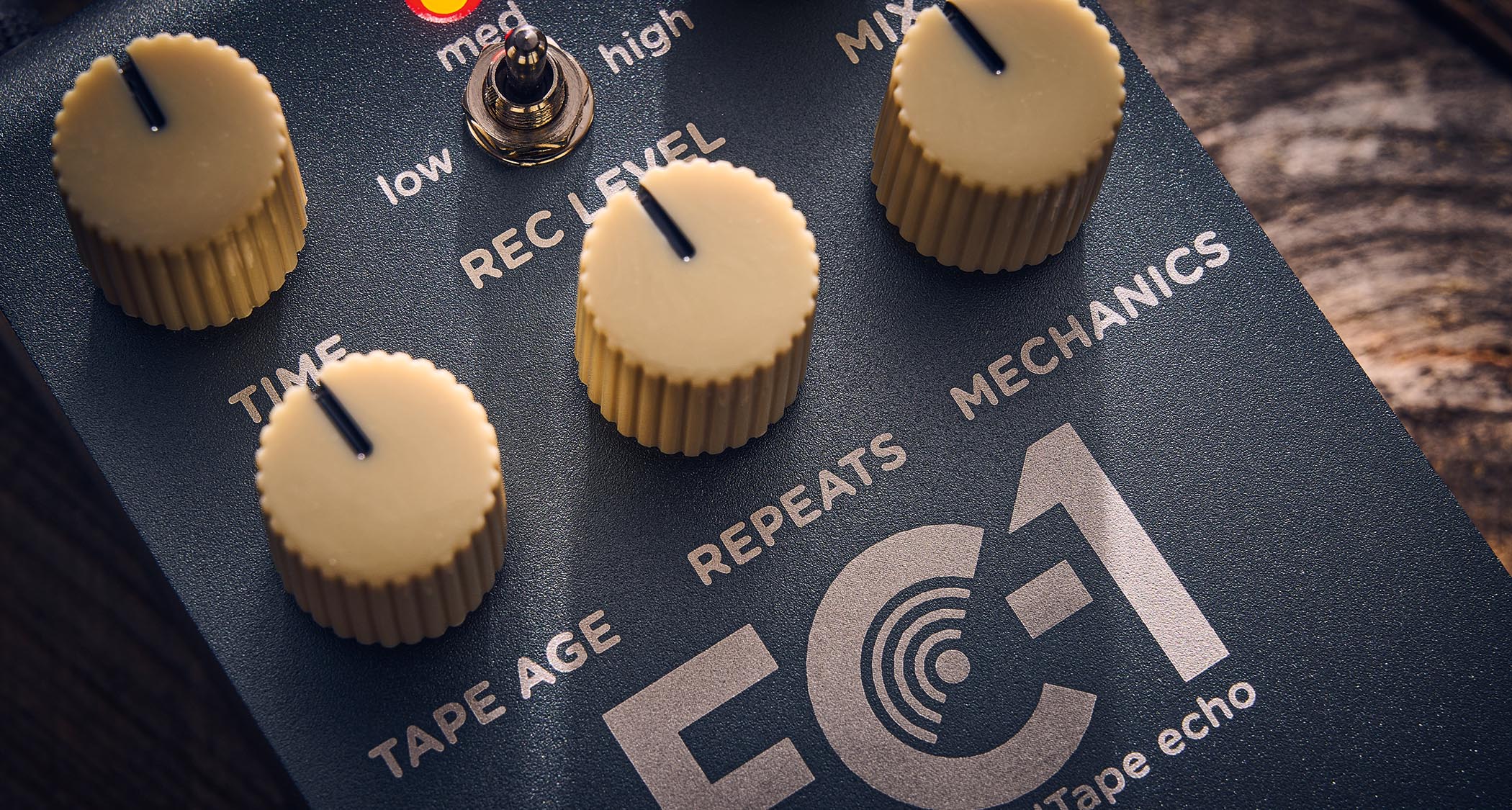 Strymon EC-1 Single Head dTape Echo: the metallic gray box has cream dials, an LED that lights up blue and/or red, and is photographed here against a wooden background.