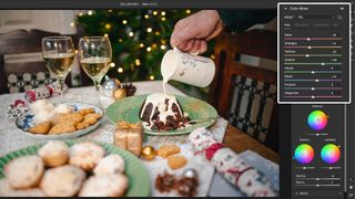 A screenshot from Adobe Lightroom showing hand holding cream and pouring it over Christmas pudding, sat on table displaying a festive spread. Bokeh fairy lights in background