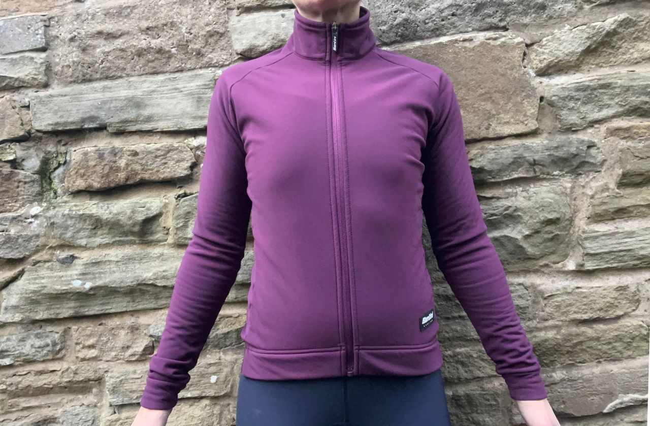 Santini RTR Winter Jacket in purple worn on a woman with a stone wall in the background