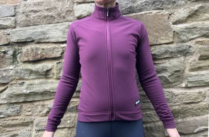 Santini RTR Wind Jacket in purple worn on a woman with a stone wall in the background