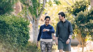 Fitbit Inspire 2 Lifestyle Sidewalk Couple Walking Lunar White Black