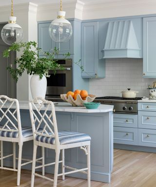 coastal light blue kitchen with blue cabinetry wooden floors and white rattan bar stools