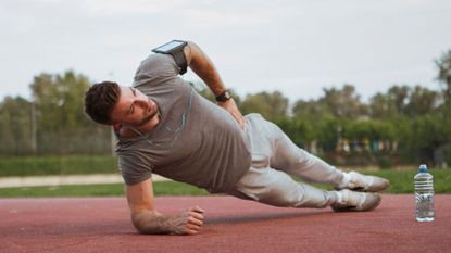 A man performing a side plank outdoors