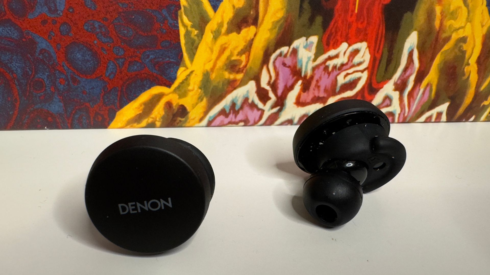 Denon PerL earbuds in front of a record