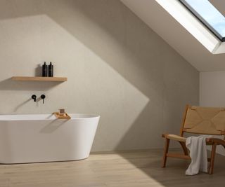 bathroom with large cream wall panels, white freestanding bath, velux window, wood and wicker chair