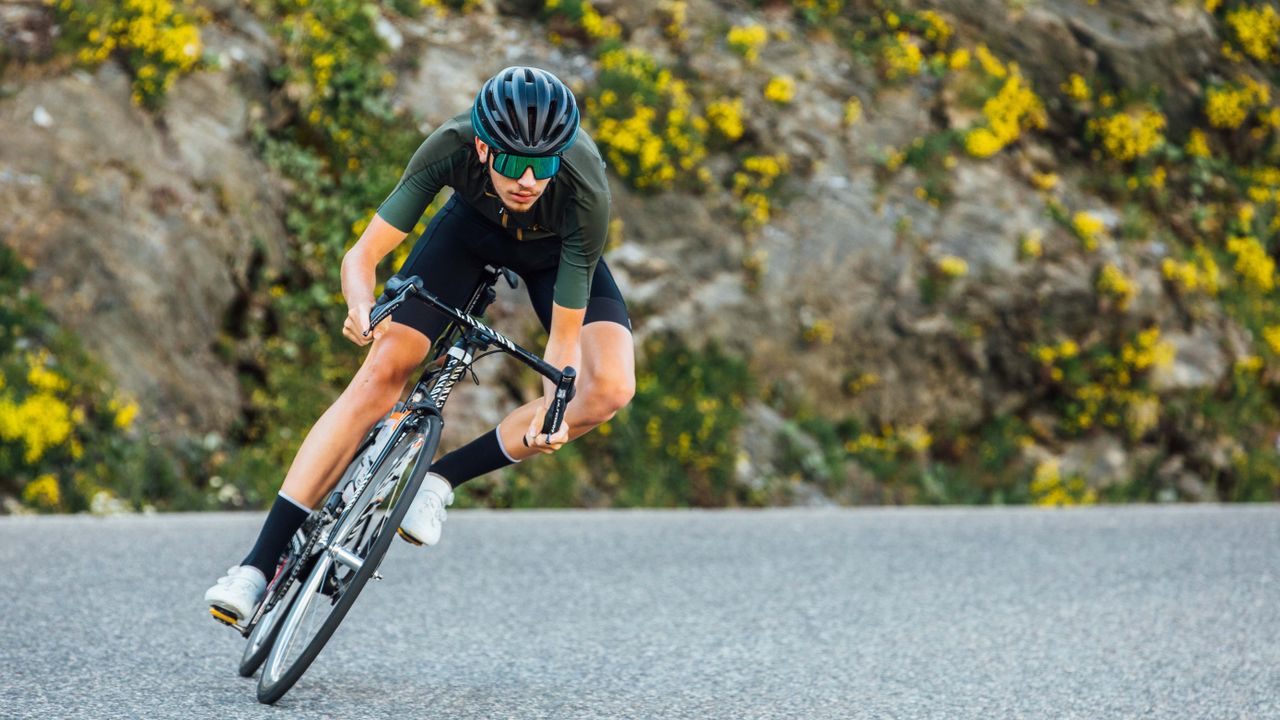 Cyclist knee out corner hard left, wearing one the best road helmets