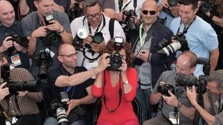 Italian actress Sophia Loren (C) holds a professional camera as she sits among photographers during a photocall for "Voce Umana" at the 67th edition of the Cannes Film Festival in Cannes, southern France, on May 21, 2014.