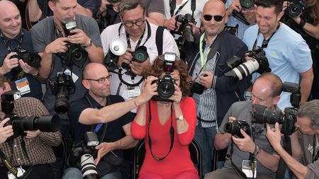 Italian actress Sophia Loren (C) holds a professional camera as she sits among photographers during a photocall for "Voce Umana" at the 67th edition of the Cannes Film Festival in Cannes, southern France, on May 21, 2014.