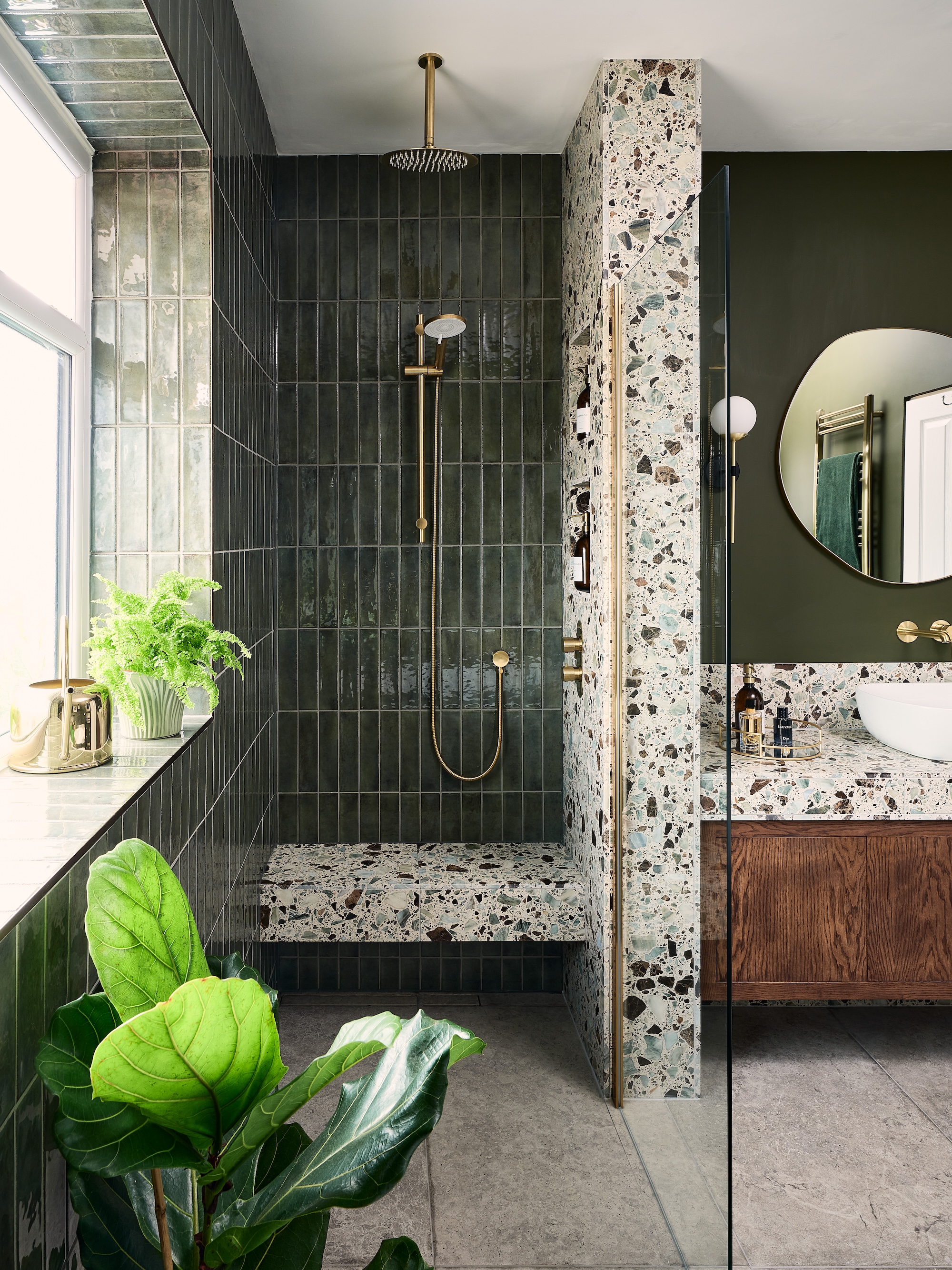 A green-tiled bathroom with a dark wood vanity and strong terrazzo feature