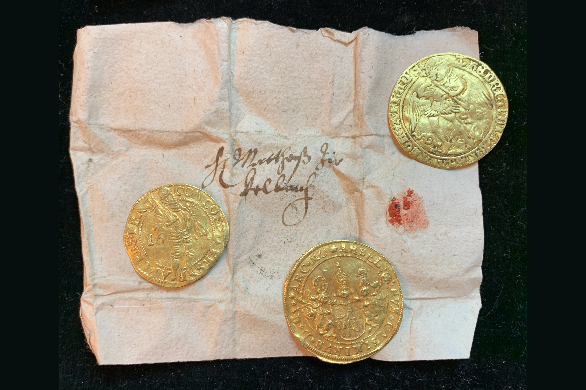 3 gold coins wrapped in old paper with cursive writing