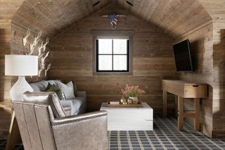 seating area in bedroom with wooden walls in loft space and leather furniture and TV
