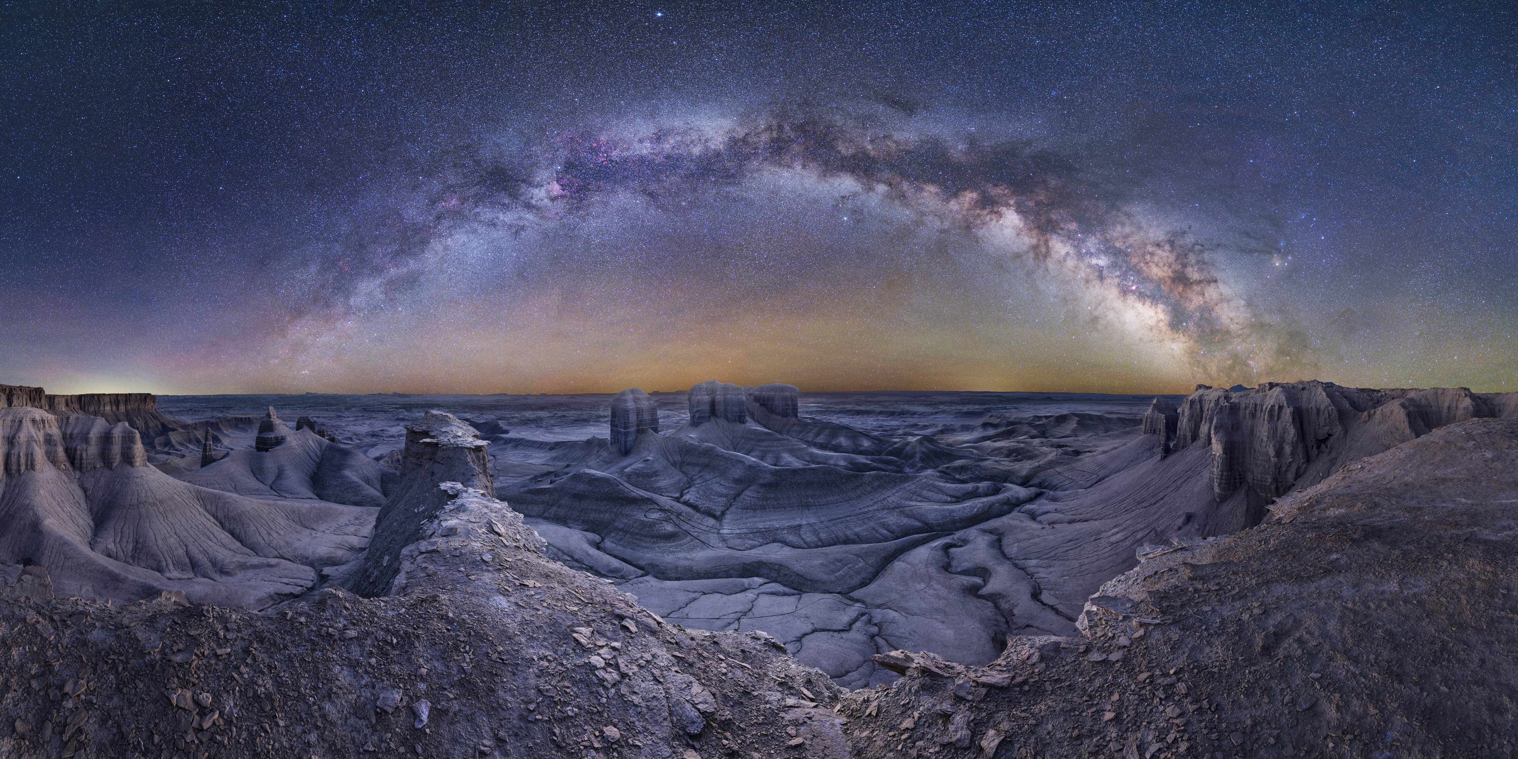 A composite image of the Milky Way galaxy streaking across the night sky in an arc over the Utah landscape