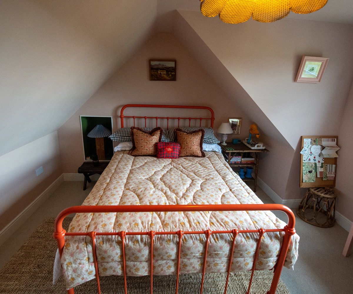 An upstairs bedroom with vaulted ceilings and orange bed railings