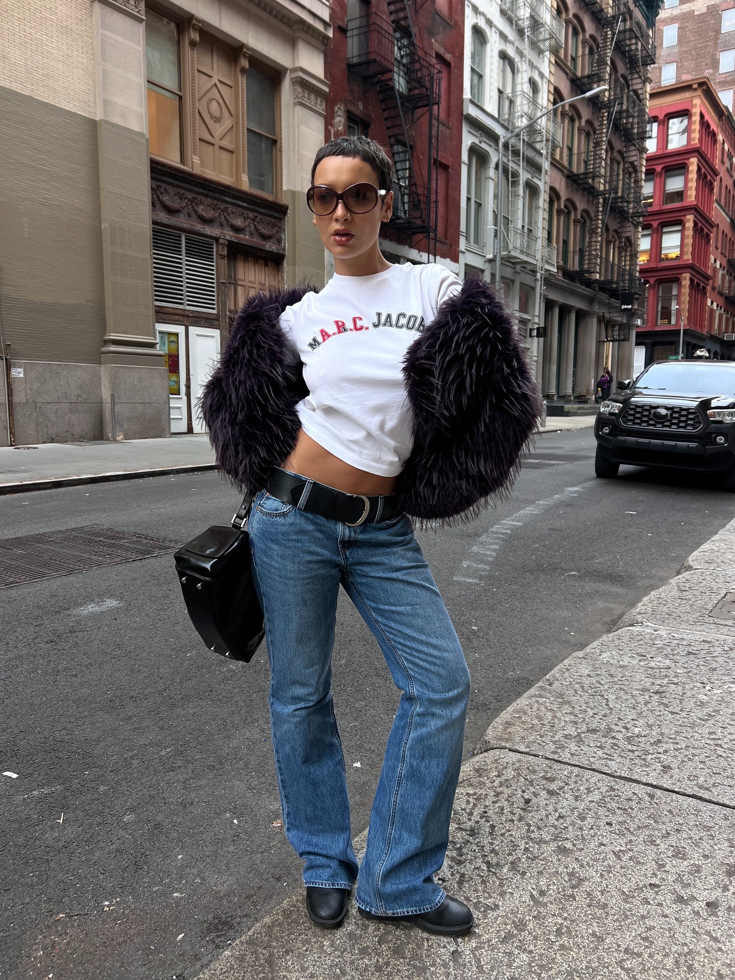 @aishafarida wears bootcut jeans with a graphic tee and faux-fur jacket.
