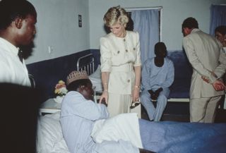 Diana, Princess of Wales (1961-1997), wearing a Catherine Walker suit, and her husband, Charles, Prince of Wales, with an patient during a visit to the Molai Centre, a leprosy hospital and rehabilitation village in Maiduguri, Nigeria, 17th March 1990. The Royal couple are on a five-day visit to Nigeria.