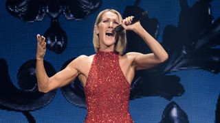 celine dion, a white woman with blonde, bobbed hair belts into a microphone while wearing a sparkly, sleeveless red dress