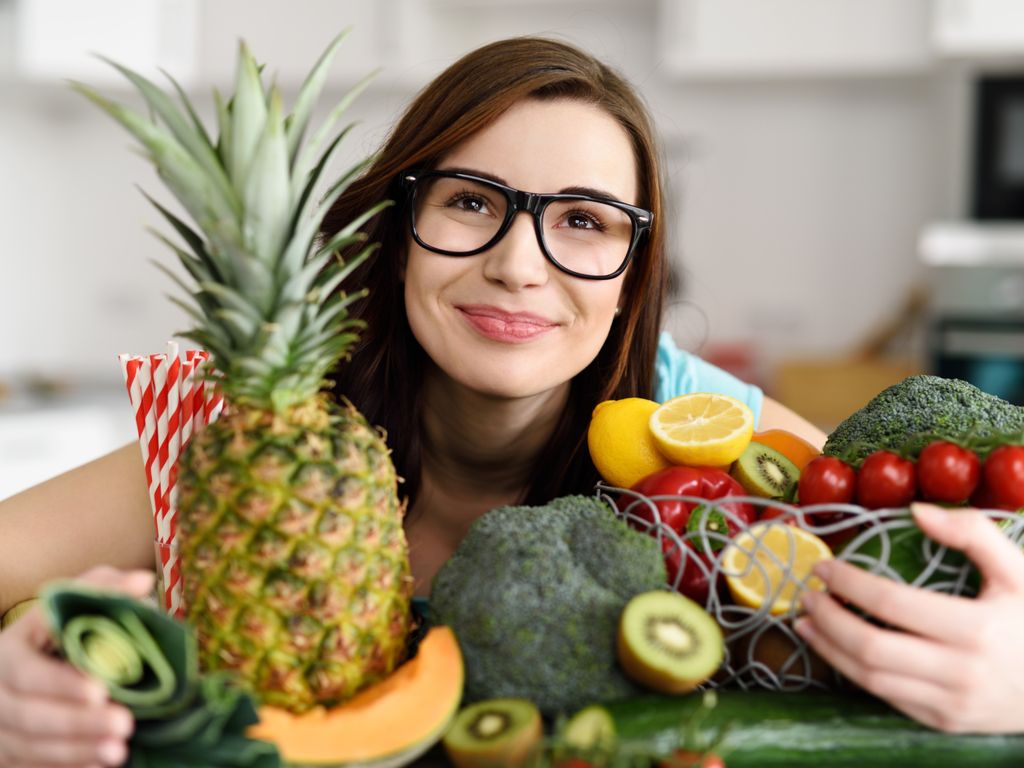 smiling woman holding fruits and vegetables