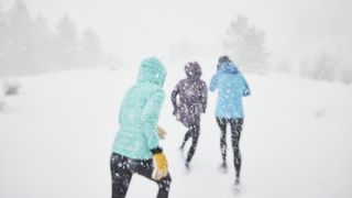 Three women running uphill in the snow