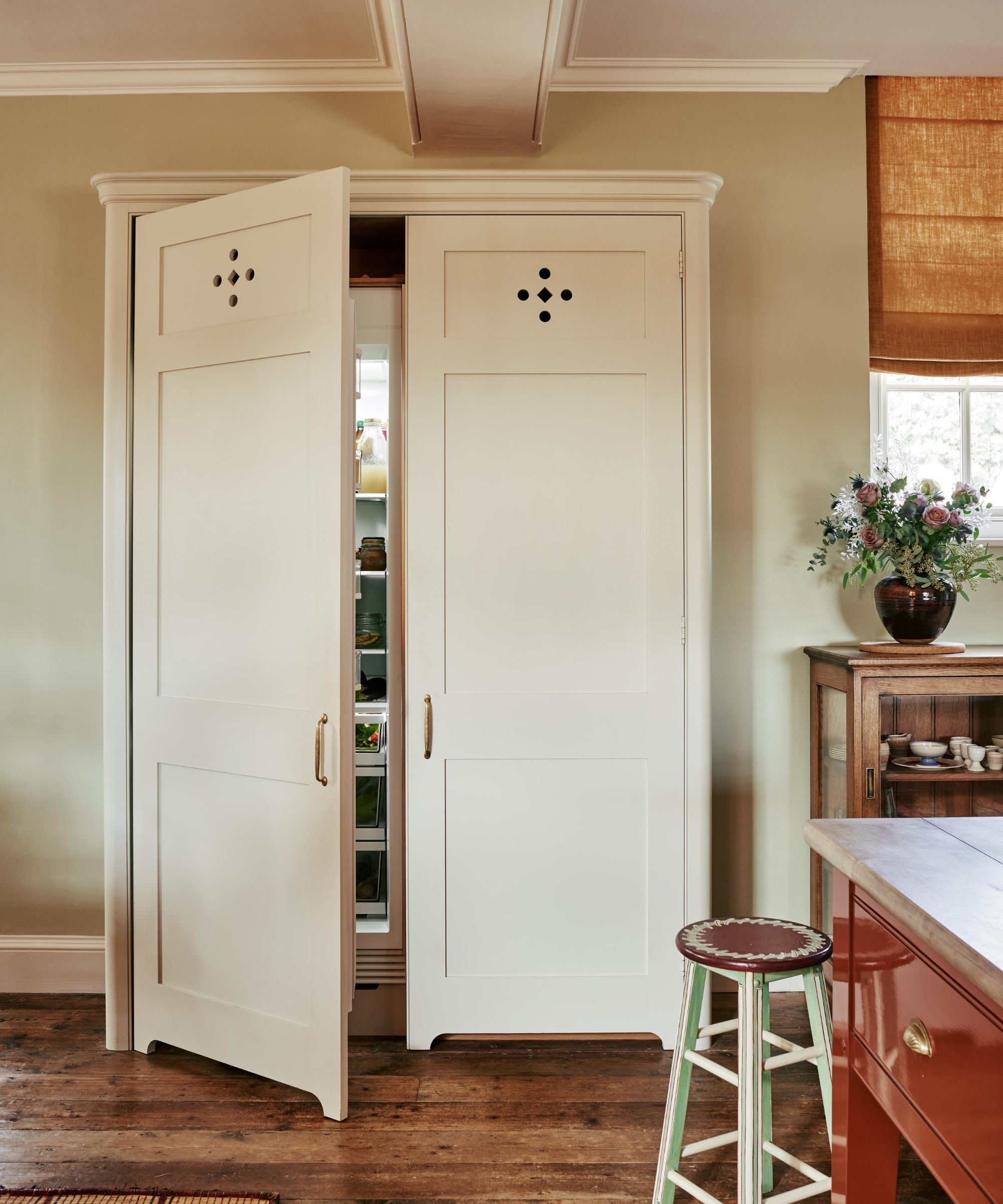 A large fridge/freezer hidden behind white larder-style doors recessed into the wall for a more traditional kitchen look