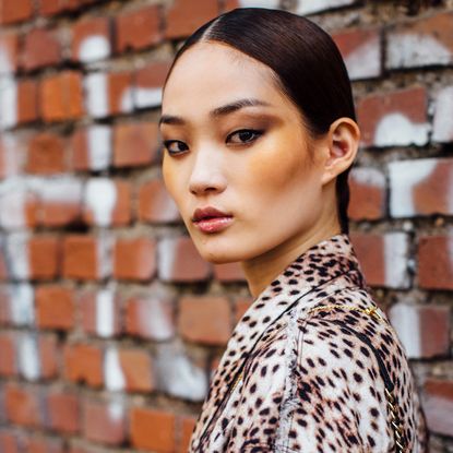 A model with bronzed skin and a low slicked back bun.