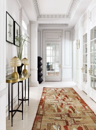 White hallway with gallery wall and red patterned rug