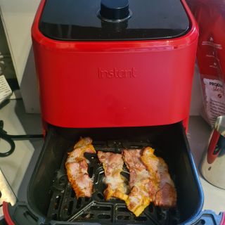 Red Instant Vortex Mini Air Fryer with open drawer containing fried bacon
